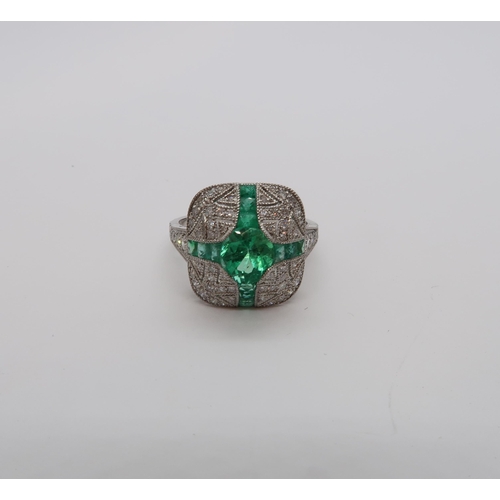 180 - A platinum Art Deco style ring set with central oval cut emerald surrounded by calibre cut emeralds ... 