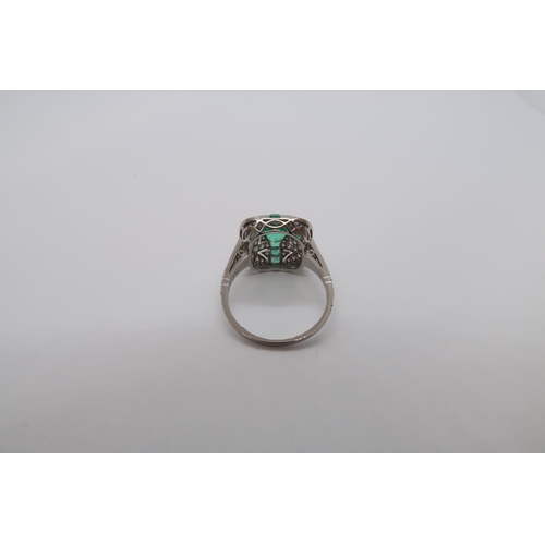 180 - A platinum Art Deco style ring set with central oval cut emerald surrounded by calibre cut emeralds ... 