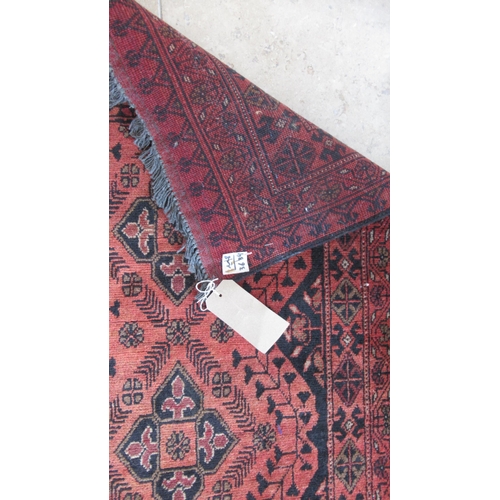 486 - An Afghan red ground hand knotted rug - 195cm x 120cm