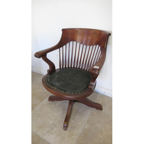 528 - An early 20th century oak revolving desk chair with a green leather seat