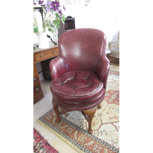 529 - A good quality 20th century walnut revolving desk chair with covered in maroon leather with a button... 