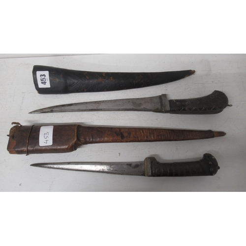 453 - Two Peshkabz daggers with horn handles and leather scabbards, 38cm and 33cm