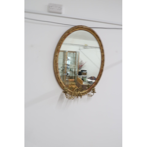 622 - A gilt framed oval mirror with triple candle holder - 80cm x 60cm