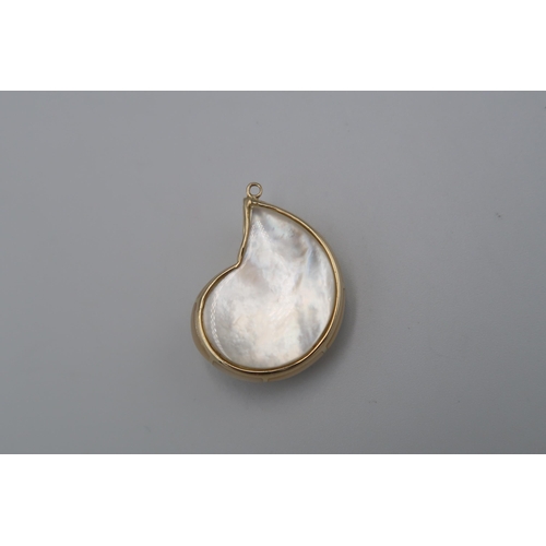 113 - A pendant in the form of a mother of pearl conch shell with central blue stone. Length 30mm. Tests g... 