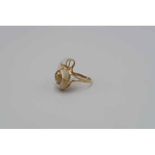 119 - A ring in the form of a mother of pearl conch shell, with green central stone. Stamped 585. Ring siz... 