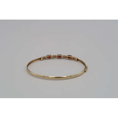 148 - A diamond and garnet bangle. Stamped 9K. Weight approx 4.78 grams