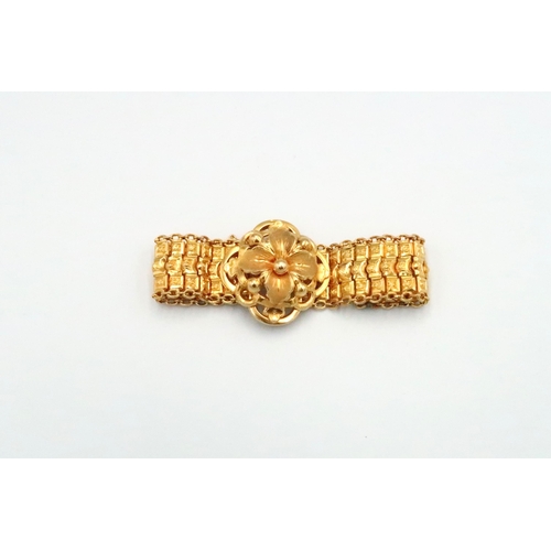 36 - An articulated bracelet with central floral panel. Length approximately 170mm. Width of panel approx... 