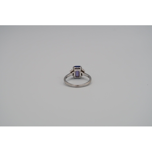 57 - An 18ct white gold tanzanite and diamond ring, the central tanzanite flanked by four baguette cut di... 