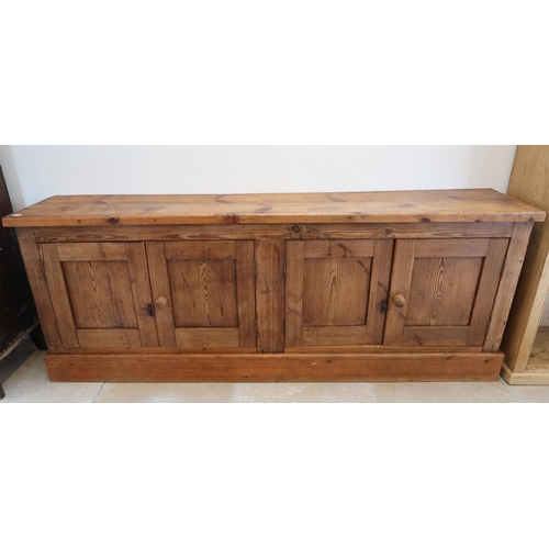 632 - A stained pine sideboard of four cupboard doors raised on plinth. 205cm wide x 39 deep x 79cm high