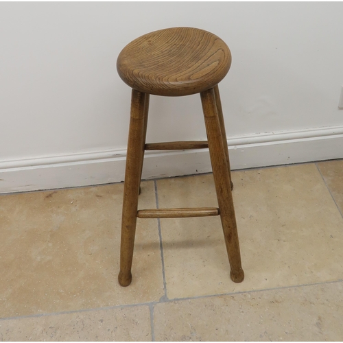 646 - An elm stool circular seat raised on turned supports joined by stretchers, 67cm high, 30cm to seat