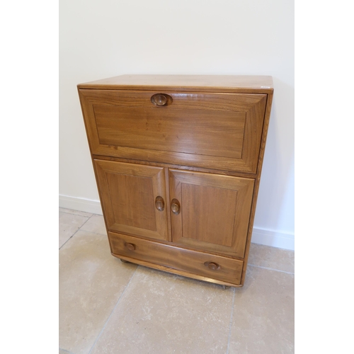 650 - An Ercol blonde elm mid 20th Century cabinet with fall front to top over two cupboard doors with a s... 