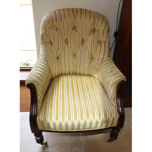 623 - A Victorian mahogany framed button back armchair raised on turned supports.