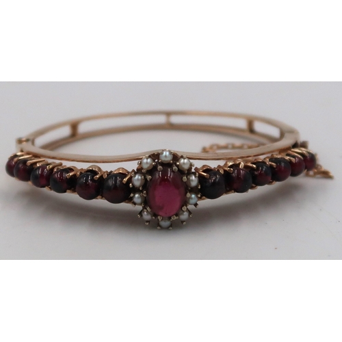 158 - A cabochon garnet and seed pearl bangle. Stamped 9. Weight 27.31 grams