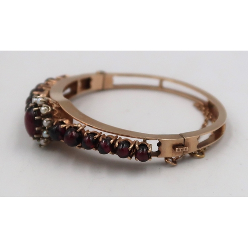 158 - A cabochon garnet and seed pearl bangle. Stamped 9. Weight 27.31 grams