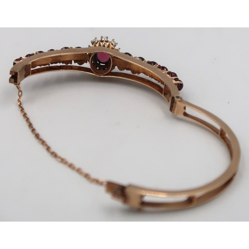 158 - A cabochon garnet and seed pearl bangle. Stamped 9. Weight 27.31 grams