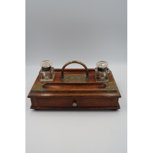 488 - An oak and brass mounted desk tidy/tray, with glass inkwells drawer below and raised on bun feet.