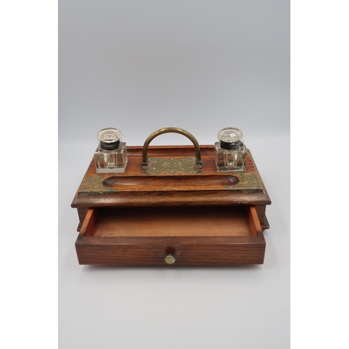 488 - An oak and brass mounted desk tidy/tray, with glass inkwells drawer below and raised on bun feet.