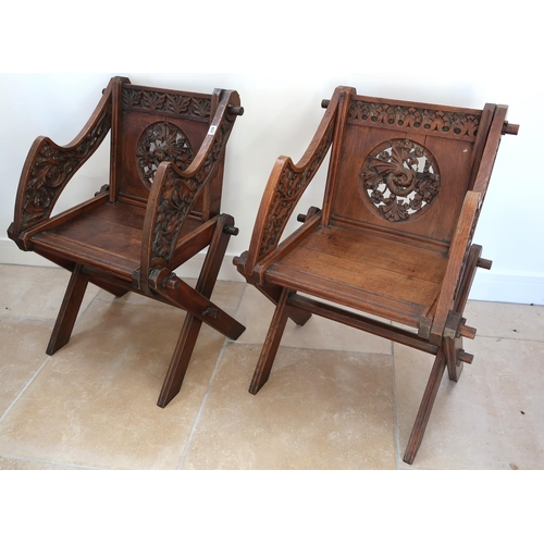 637 - A pair of oak Glastonbury hall chairs, heavily carved with cross frame to seat joined by stretcher, ... 