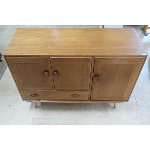 668 - An Ercol blonde elm Windsor Centenary Cabinet of two doors over single drawer flanked by door raised... 