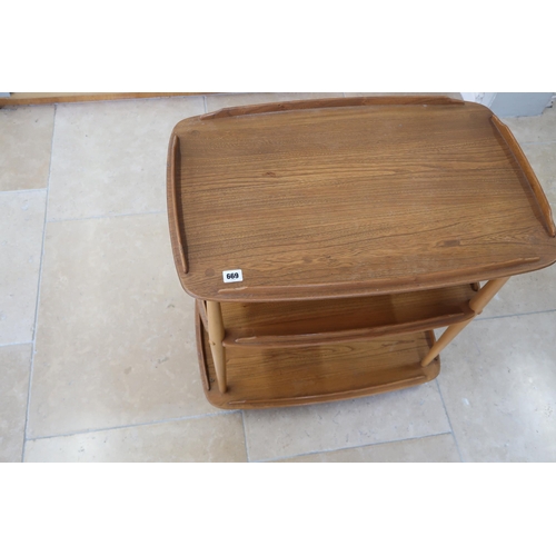 669 - An Ercol blonde elm Windsor three tier drinks trolley raised on casters. 71cm long x 46cm wide x 76c... 