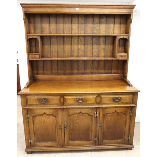 674 - An Oak dresser, plate rack with two small drawers over base of three drawers above three doors raise... 