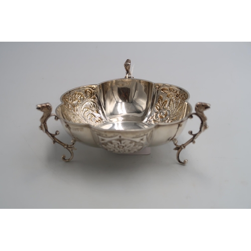 338 - A hallmarked silver sweet meat dish raised on three supports with animal head handles, embossed foli... 