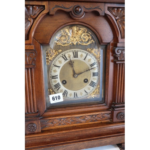 610 - An 8 day oak striking mantle clock in a walnut case - Height 47cm - has key and pendulum, case in go... 