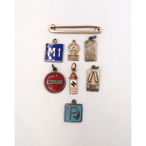 200 - A 9ct gold marked pin with two 9ct gold hallmarked road sign charms and five silver charms