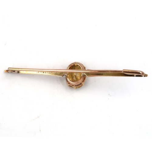 220 - An oval citrine bar brooch. Stamped 15. Weight 3.89 grams.