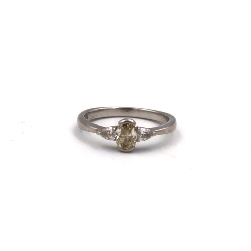 222 - A platinum three stone ring. With central oval yellow diamond estimated 0.45ct with a pear shape dia... 