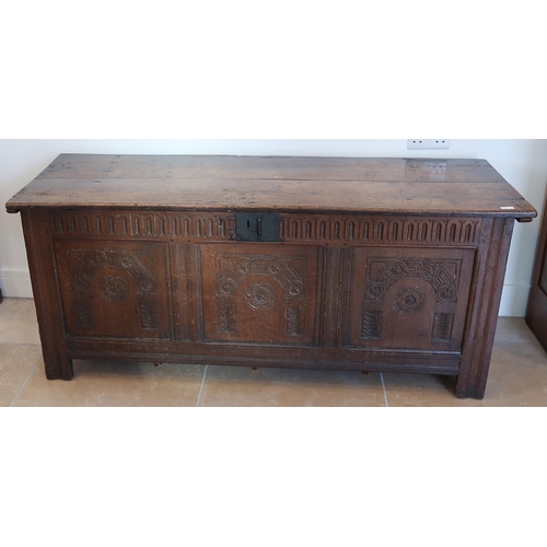 705 - An antique oak coffer - Three carved panels to front lift top opening to reveal candle box raised on... 