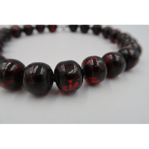 175 - A string of dark red beads (possibly bakelite but not tested) Length 43cm