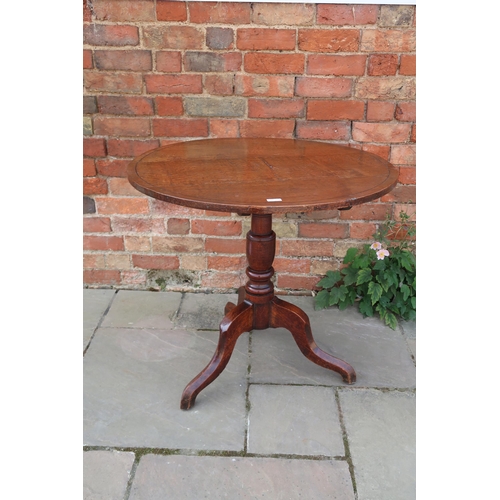 713 - A Georgian oak circular tilt top tripod table raised on pad feet, 80cm x 74cm high