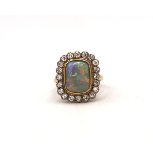  A black opal and brilliant cut diamond cluster ring. Opal approximately 13.5mm by 11mm, vibrant play... 