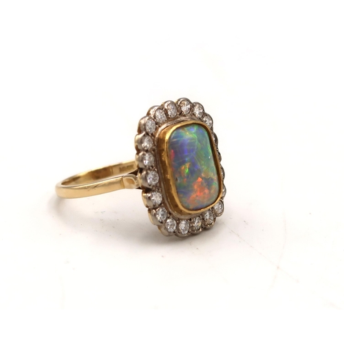  A black opal and brilliant cut diamond cluster ring. Opal approximately 13.5mm by 11mm, vibrant play... 