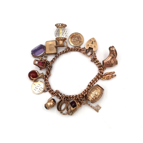 16 - A curb link bracelet with padlock clasp suspending 14 assorted charms. Tested as or with marks indic... 