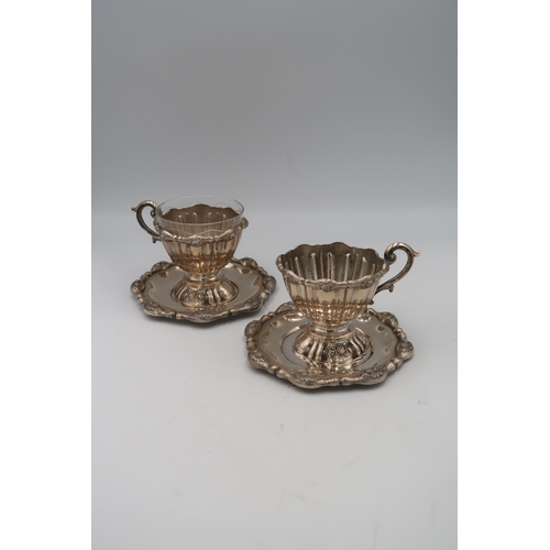 343 - A pair of Austrian silver punch cups with single handles decorated with floral sprays on trays, appr... 