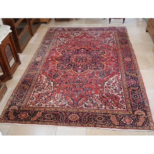 571 - A large Persian handmade rug with a red field, 370 by 250cm.