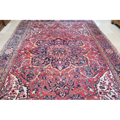 571 - A large Persian handmade rug with a red field, 370 by 250cm.