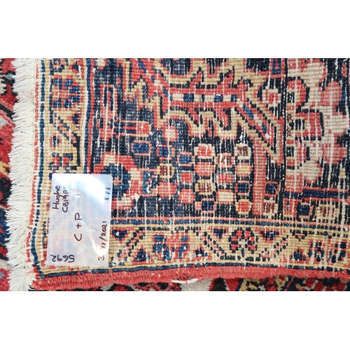 571 - A large Persian handmade rug with a red field, 370 by 250cm.