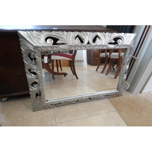 719 - A Circa 1900 carved oak framed mirror painted later silver. 74cm x 33cm. (Good condition).