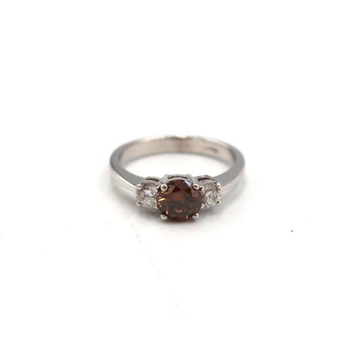 153 - An 18ct diamond three stone ring - The central round brilliant cut diamond of fancy champagne colour... 