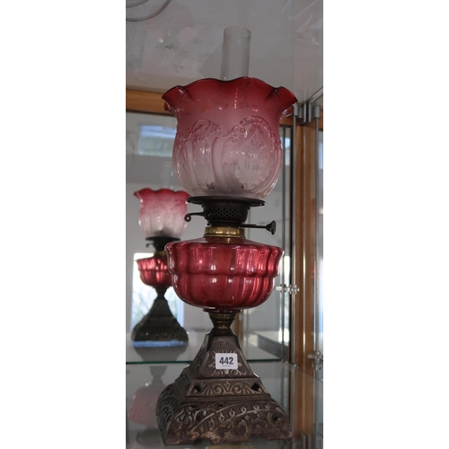 442 - A vintage oil lamp, the shade of etched and moulded cranberry glass, with fluted reservoir, on pierc... 