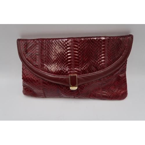 451 - A Jane Shilton burgundy snakeskin hand bag, of clutch foldover form, 29 by 16cm, complete with cloth... 