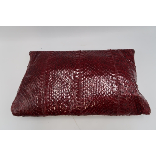 451 - A Jane Shilton burgundy snakeskin hand bag, of clutch foldover form, 29 by 16cm, complete with cloth... 