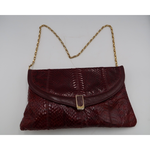 451 - A Jane Shilton burgundy snakeskin hand bag, of clutch foldover form, 29 by 16cm, complete with cloth... 