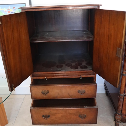 660 - An early 20th century walnut veneered drinks cabinet, the two panel doors opening to reveal shelves,... 