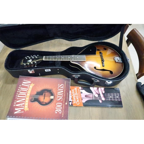 439 - A mandolin with curved back and later added Gibson logo label, cased and a number of mandolin books.