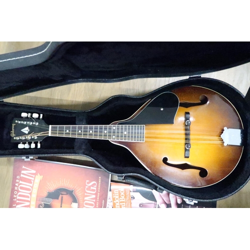 439 - A mandolin with curved back and later added Gibson logo label, cased and a number of mandolin books.