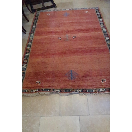 571 - A red ground woolen rug with geometric boarders - the field covered in animal motifs - 2.8m x 2.07m